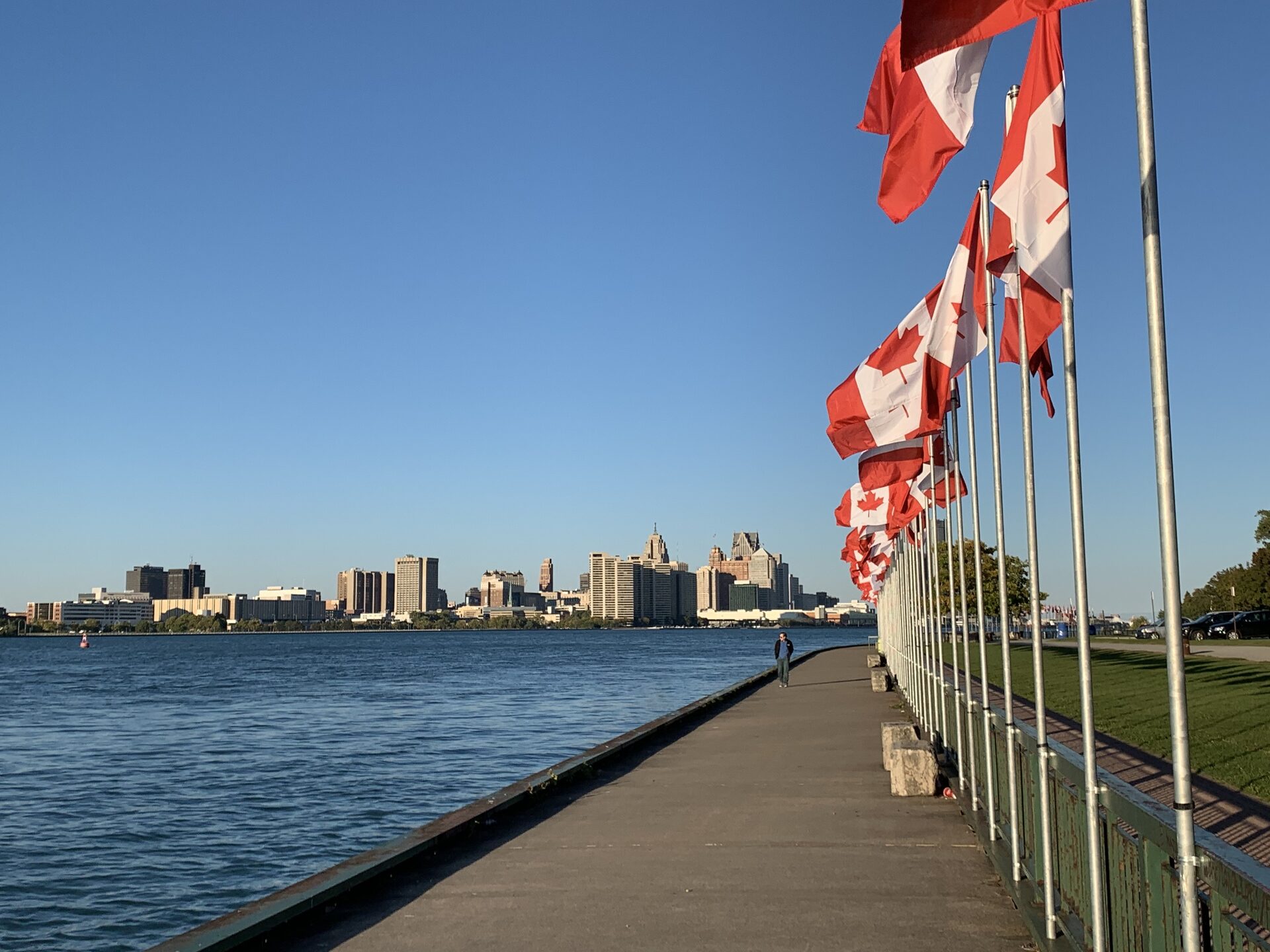 The Detroit skyline across the river, seen from Windsor's riverfront lined with Canadian flags